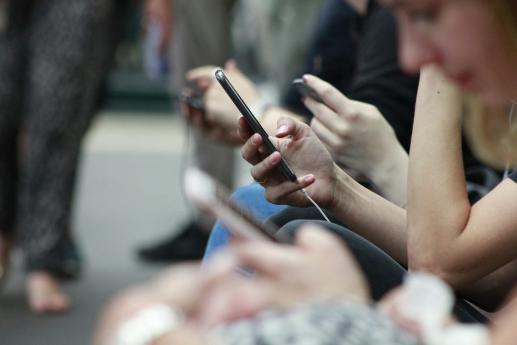 Image of a bunch of people outside on there smartphones.